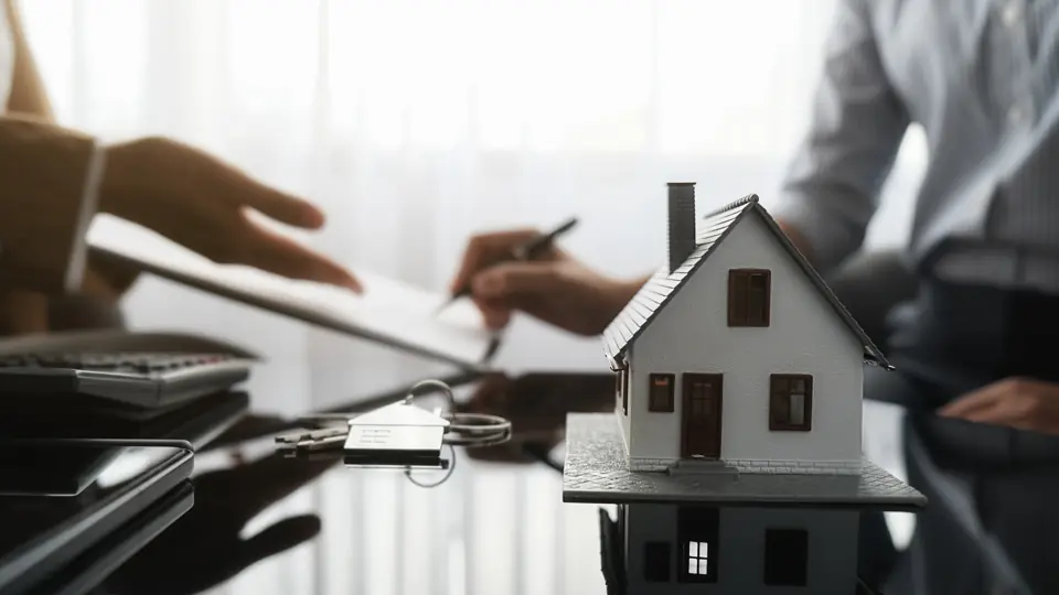 Homeowner reviewing an insurance claim with a model house and keys on the desk