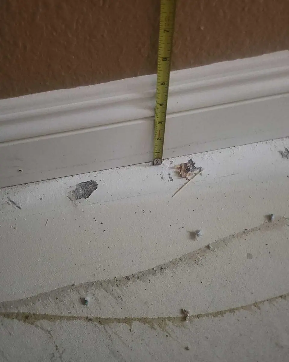 Tape measure marking the water line on a wall before flood cuts